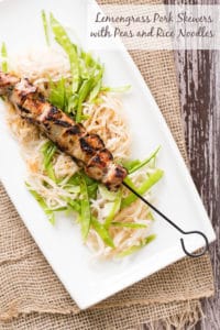 Lemongrass pork skewers with peas and rice noodles on white plate