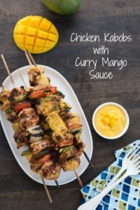 Chicken kabobs and white plate and curry mango sauce in bowl