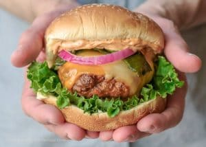 Hands holding chorizo poblano cheeseburger