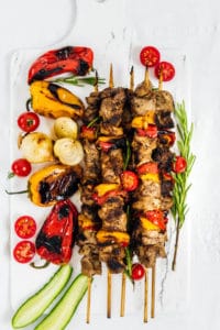 Lamb shish kabobs and roasted peppers on marble cutting board