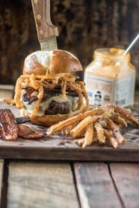 Spicy and smokey candied bacon burger and fries on cutting board