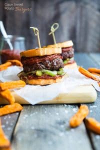 Cajun burgers on parchment paper surrounded by fries