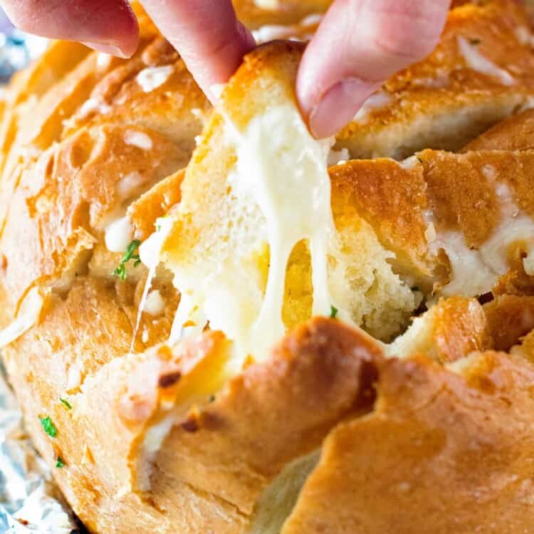 Hand pulling off a piece of Grilled Cheesy Garlic Pull Apart Bread
