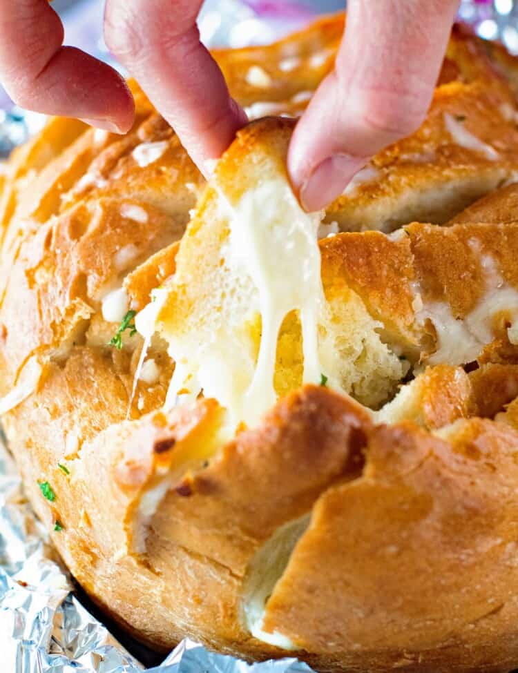 Hand pulling off a piece of Grilled Cheesy Garlic Pull Apart Bread