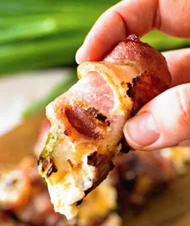 Hand holding grilled bacon wrapped jalapeno popper