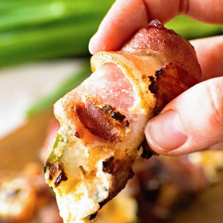 Hand holding grilled bacon wrapped jalapeno popper