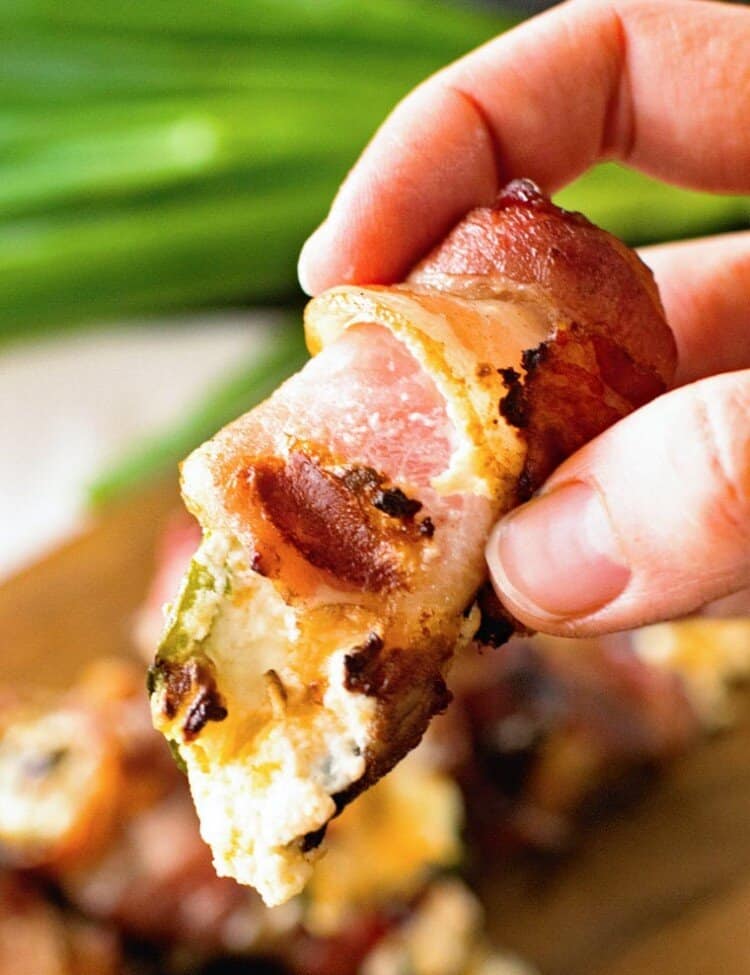 Hand holding grilled bacon wrapped jalapeno popper