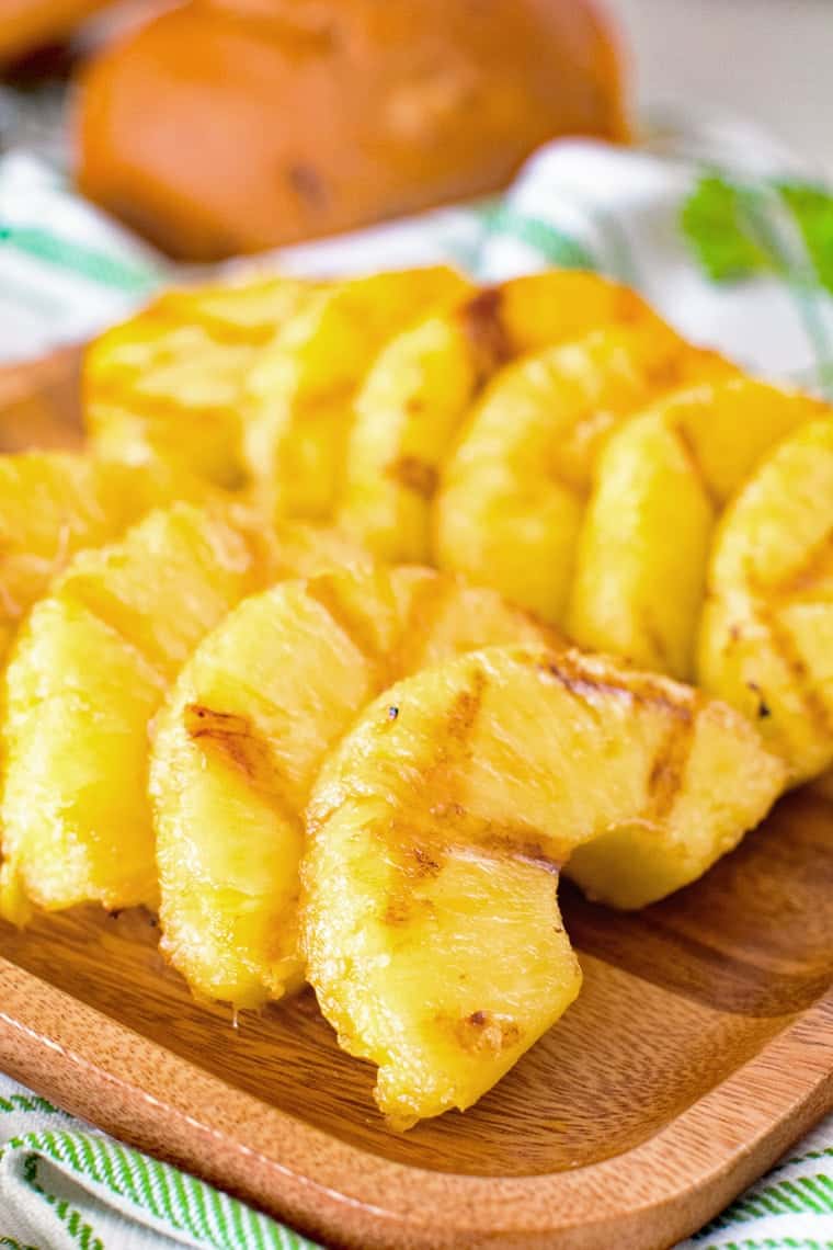 half circle slices of grilled pineapple on wood platter