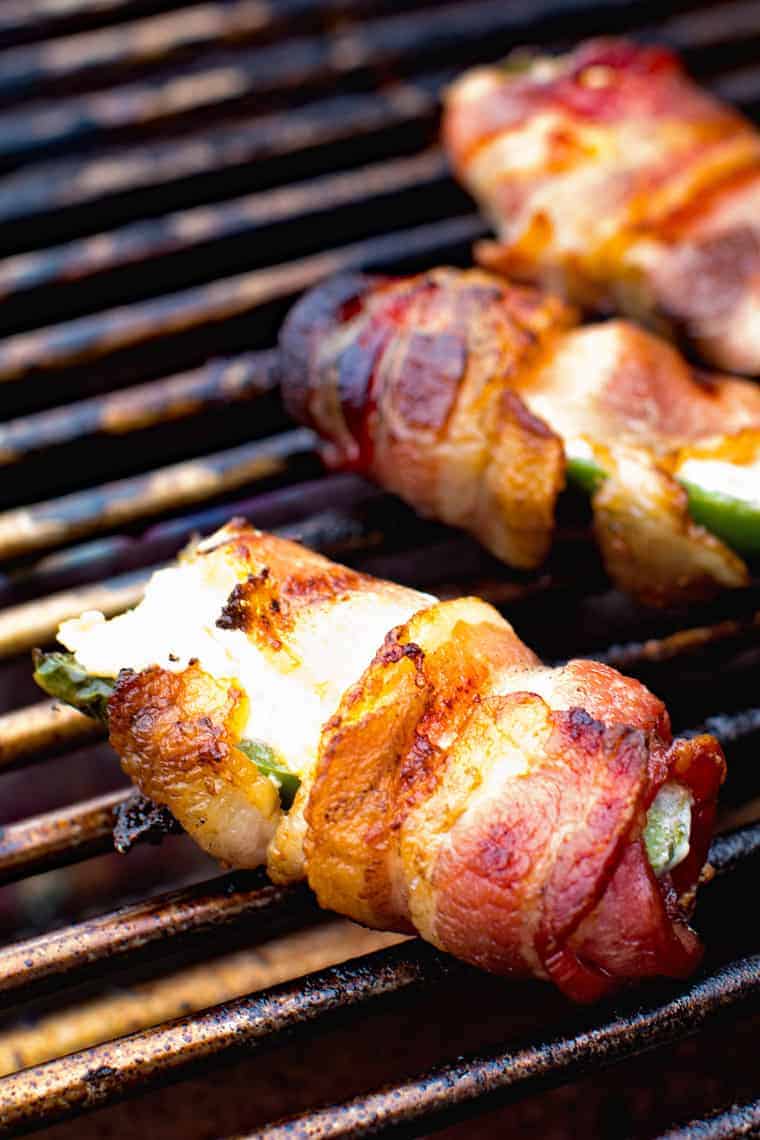 Jalapeno poppers wrapped in bacon on a grill grate