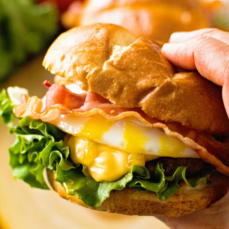 Hand holding fried egg hamburger