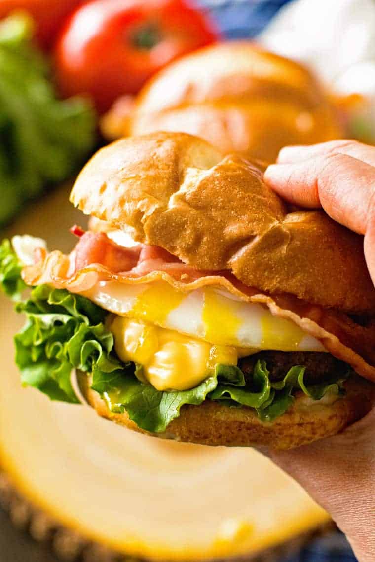 Hand holding fried egg hamburger