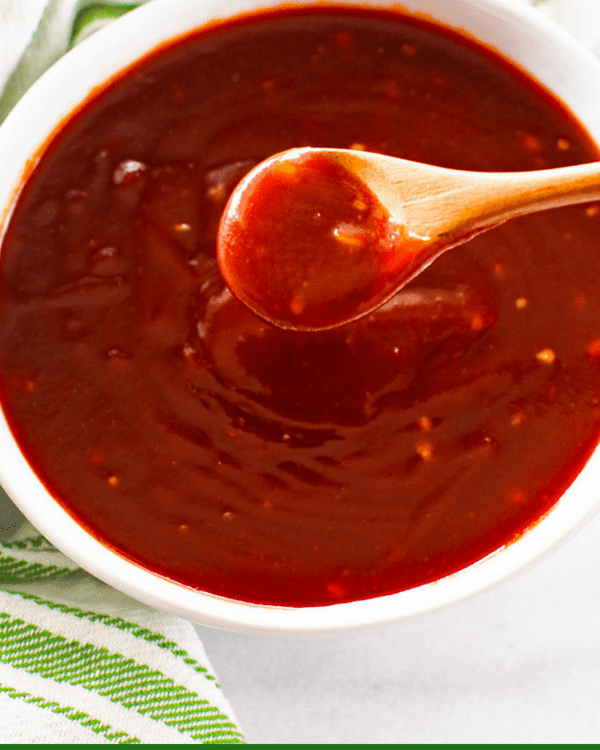 Sweet and Sassy BBQ Sauce in white bowl with small wooden spoon