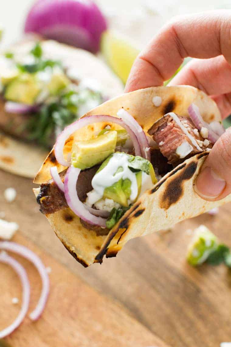Steak Tacos topped with avocado, red onion and sour cream.