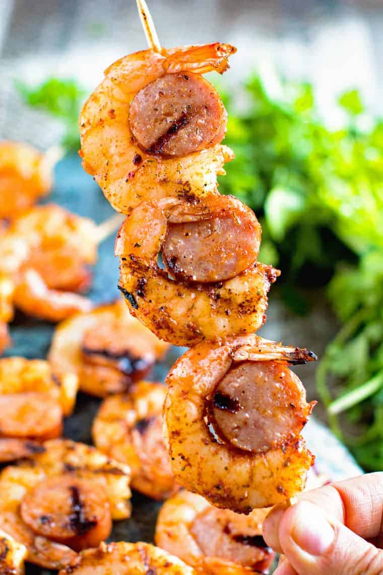 hand holding Sausage and grilled shrimp kabobs