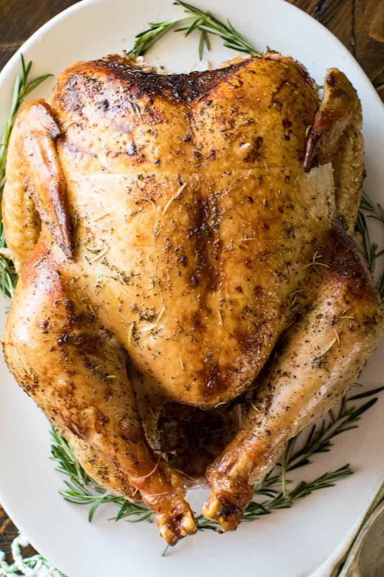 Overhead image of Smoked Turkey on white platter with thyme around it.