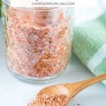 small wood spoon scooping out dry rub for ribs from glass jar