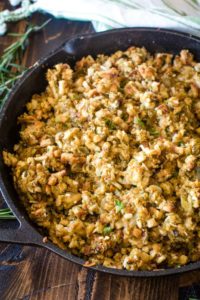 Cast iron skillet filled with smoked stuffing on a cutting board