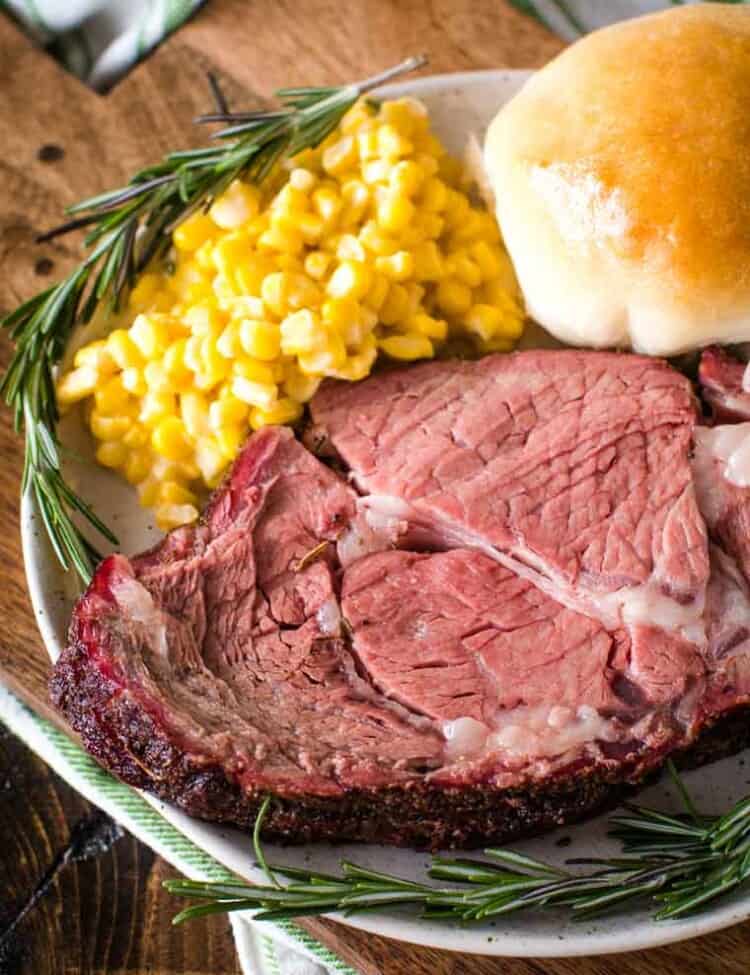 Smoked Prime Rib slice on plate with corn and dinner roll