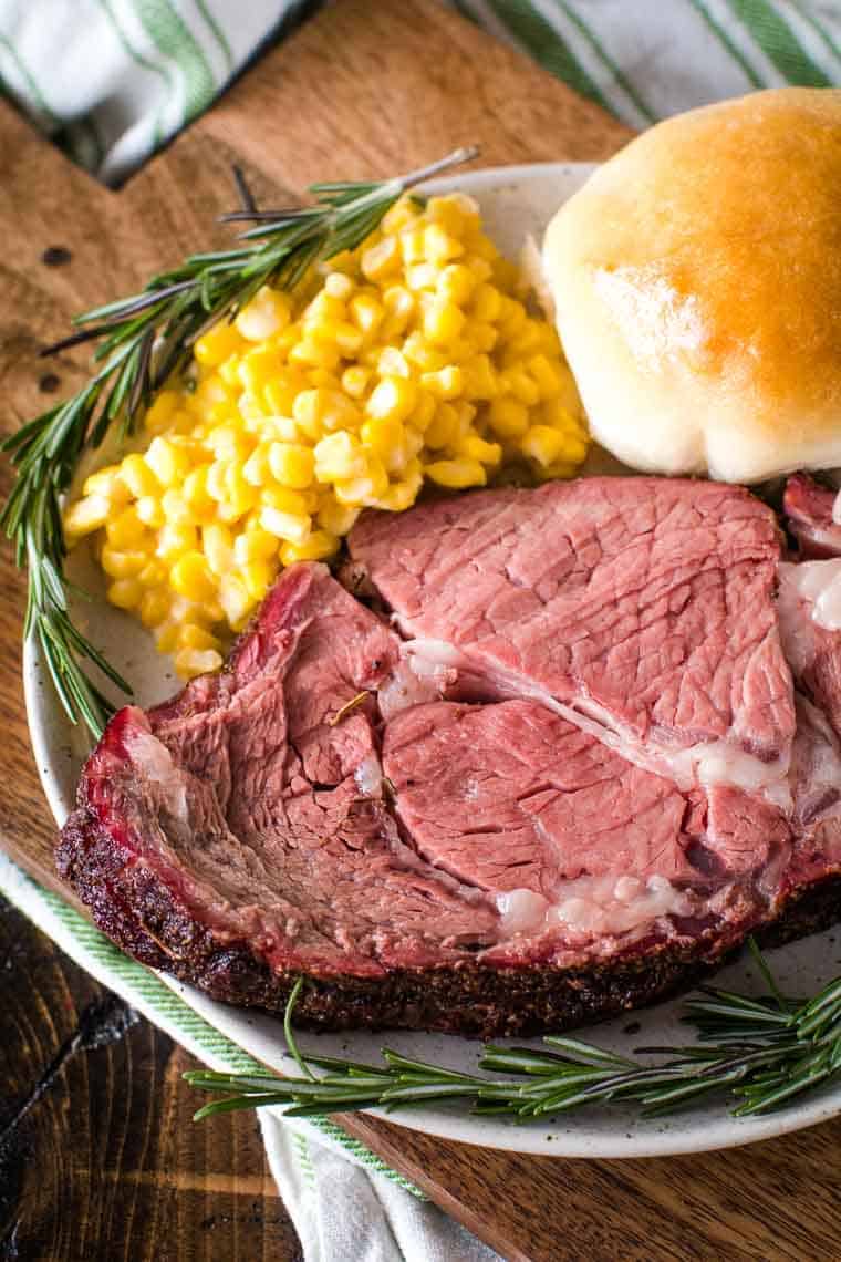 Smoked Prime Rib slice on plate with corn and dinner roll