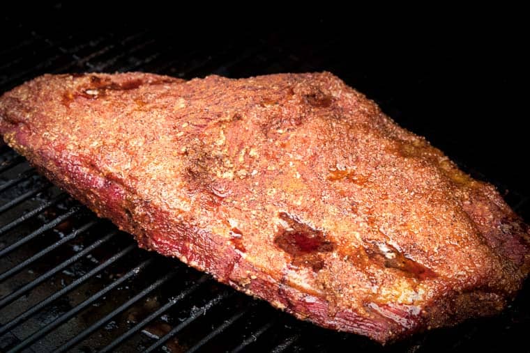 electric smoker grates with seasoned brisket being cooked on it