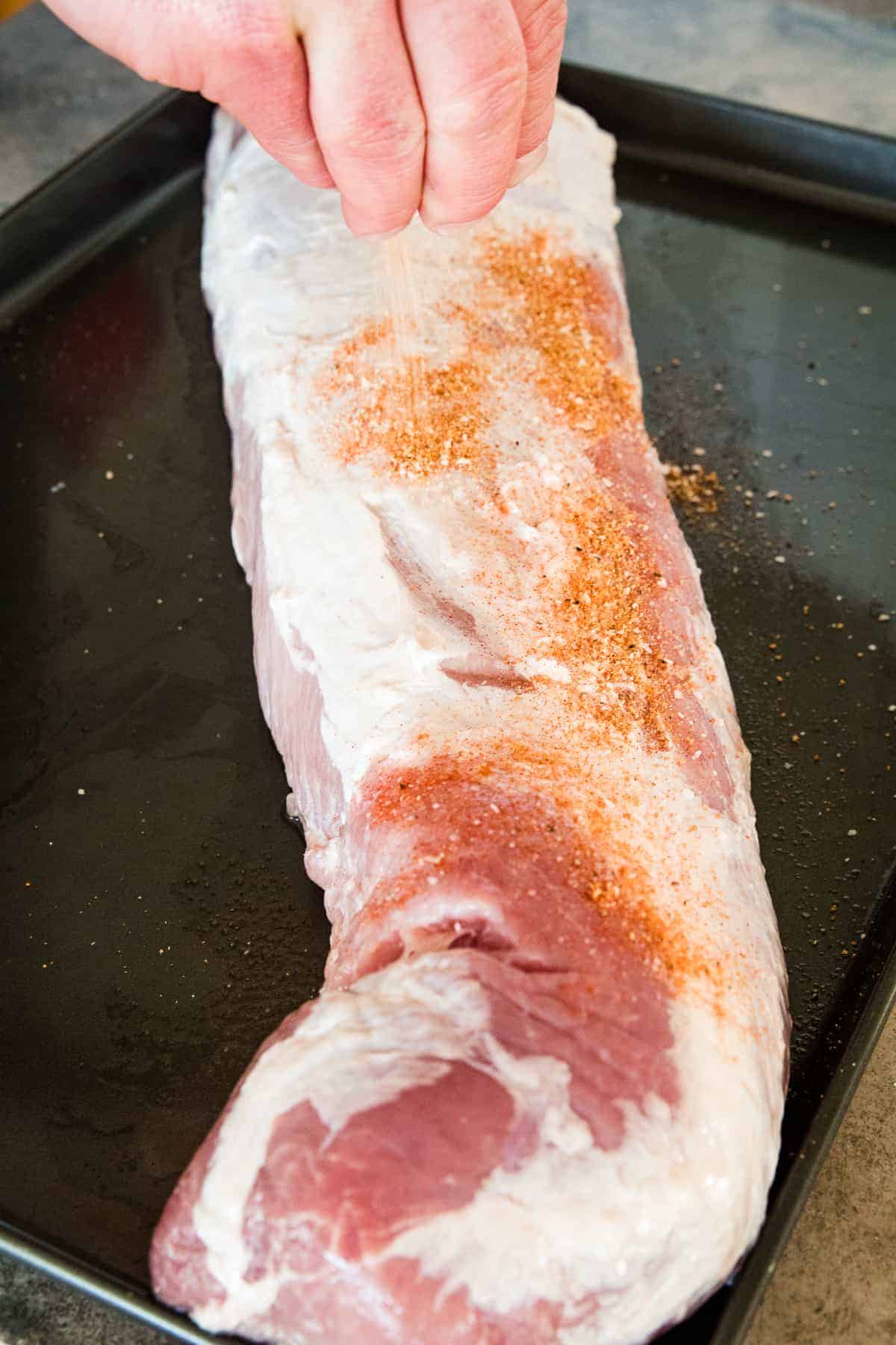 Sprinkling dry rub on pork loin
