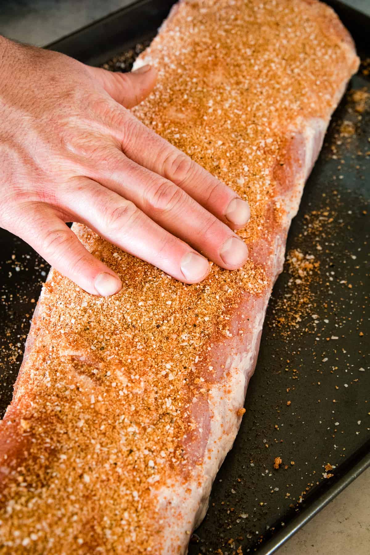 Hand rubbing dry rub on pork loin