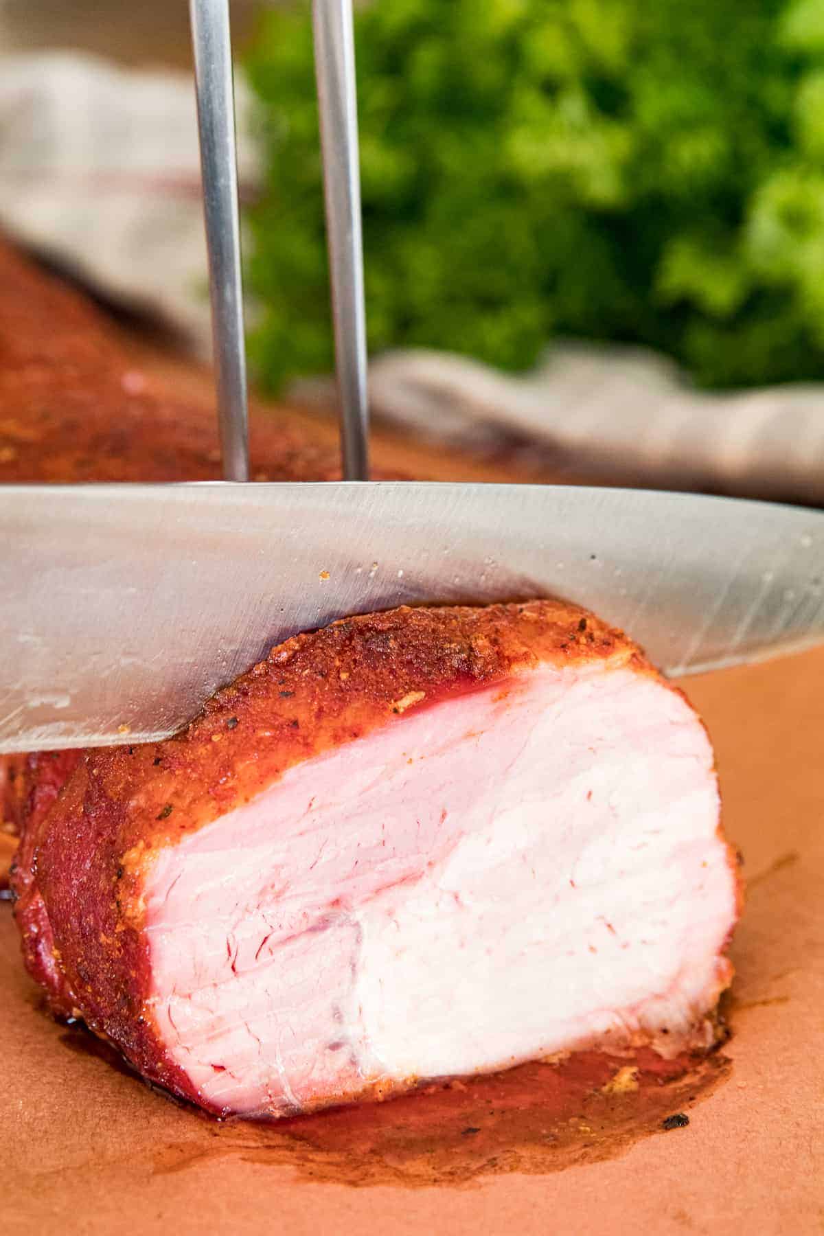 Knife cutting a piece of smoked pork loin off