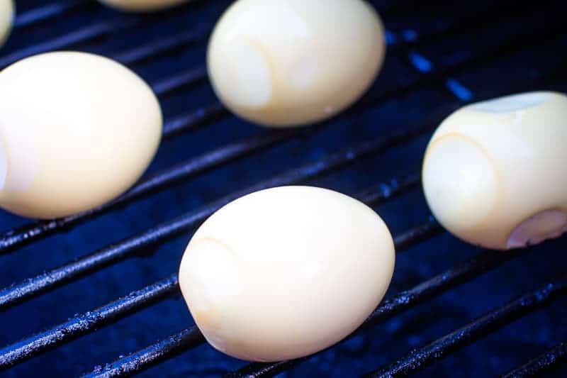 Peeled eggs on smoker rack being smoked