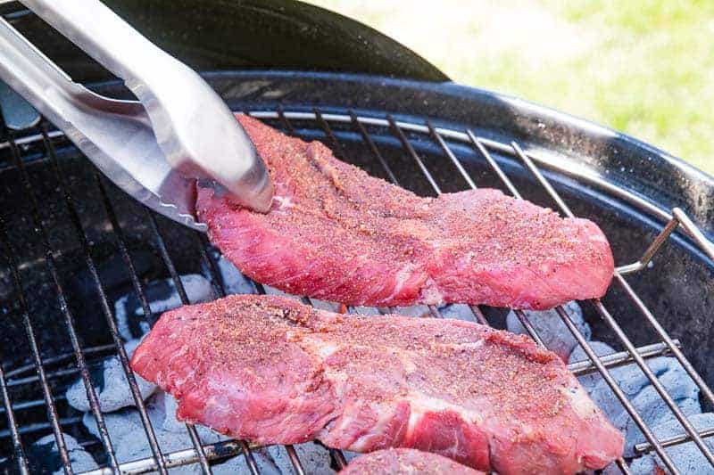 Raw steaks on charcoal grill