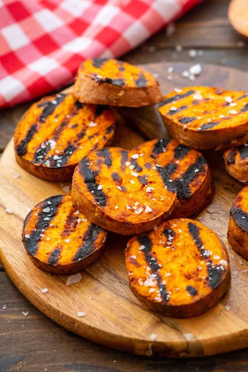 Grilled slices of sweet potatoes sprinkled with sea salt on wood circle platter