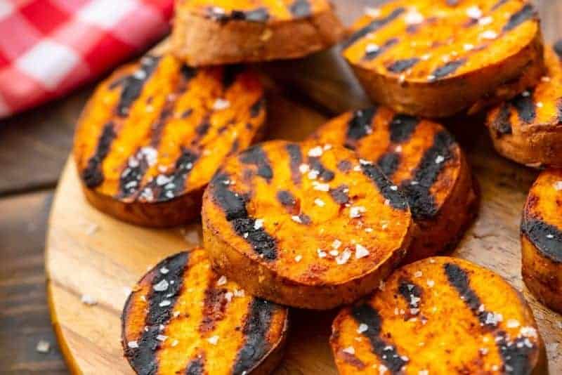Sweet potatoes with charred marks from grilling on wooden platter