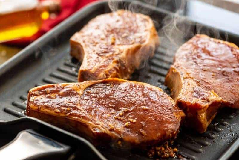 Grill pan with pork chops on it and steaming raising off of them