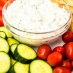 Tzatziki Sauce pinterest image, glass bowl full of sauce surrounded by cut up vegetables.