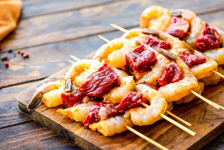 Raw Steak and Shrimp Kabobs on wood cutting board