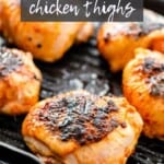 Grilled chicken thighs being cooked on a pan.
