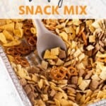 Traeger snack mix in a foil tray with a spoon