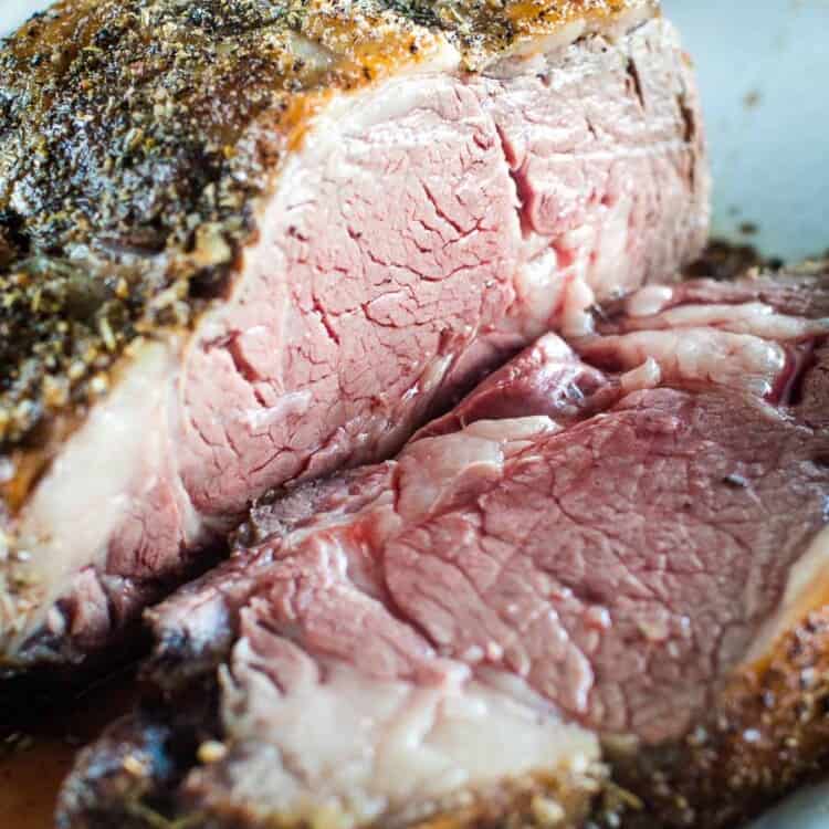 Grilled prime rib sliced on a white serving tray.