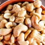 Smoked nuts in a white and red bowl.