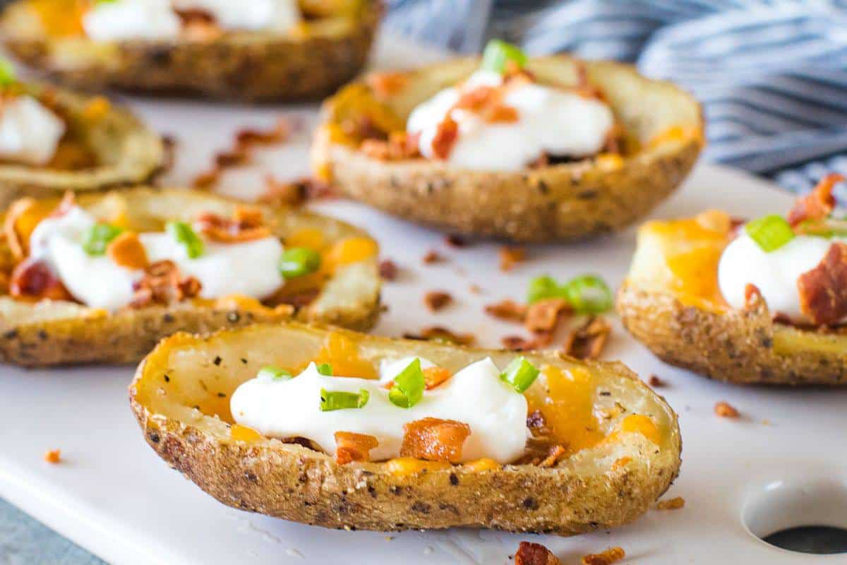 Potato Skins with sour cream, chives, and bacon on cutting board