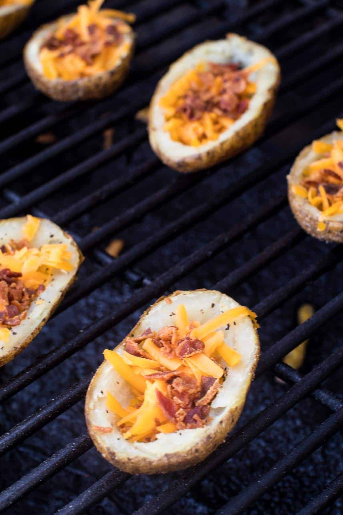 Potato Skins on Smoker filled with bacon bits and shredded cheese.