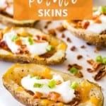 Smoked Potato Skins Pin Image. Smoked potatoes skins with sour cream, green onion, and bacon on a white cutting board.