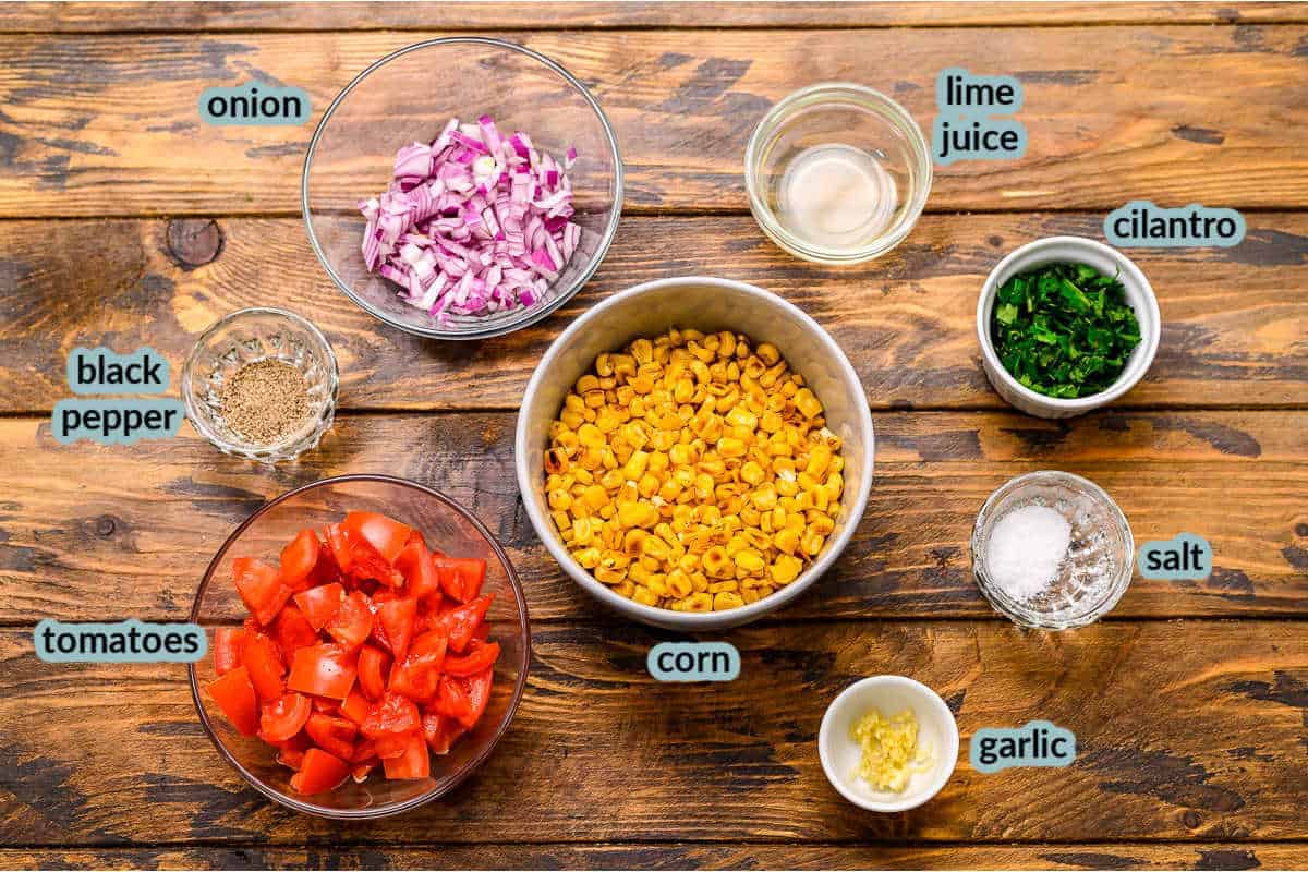 Ingredients for corn salsa including tomatoes corn onions cilantro salt lime juic pepper garlic
