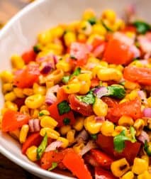Bowl with grilled corn tomatoes onions and lime dressing