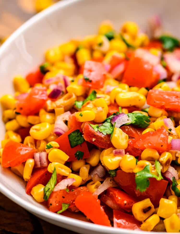 Bowl with grilled corn tomatoes onions and lime dressing