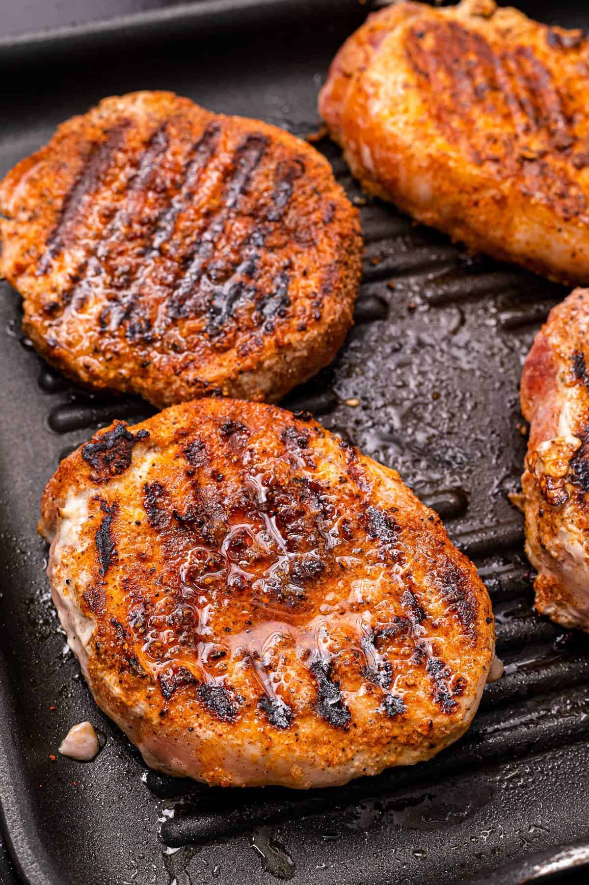A grill pan with seasoned pork chops on it