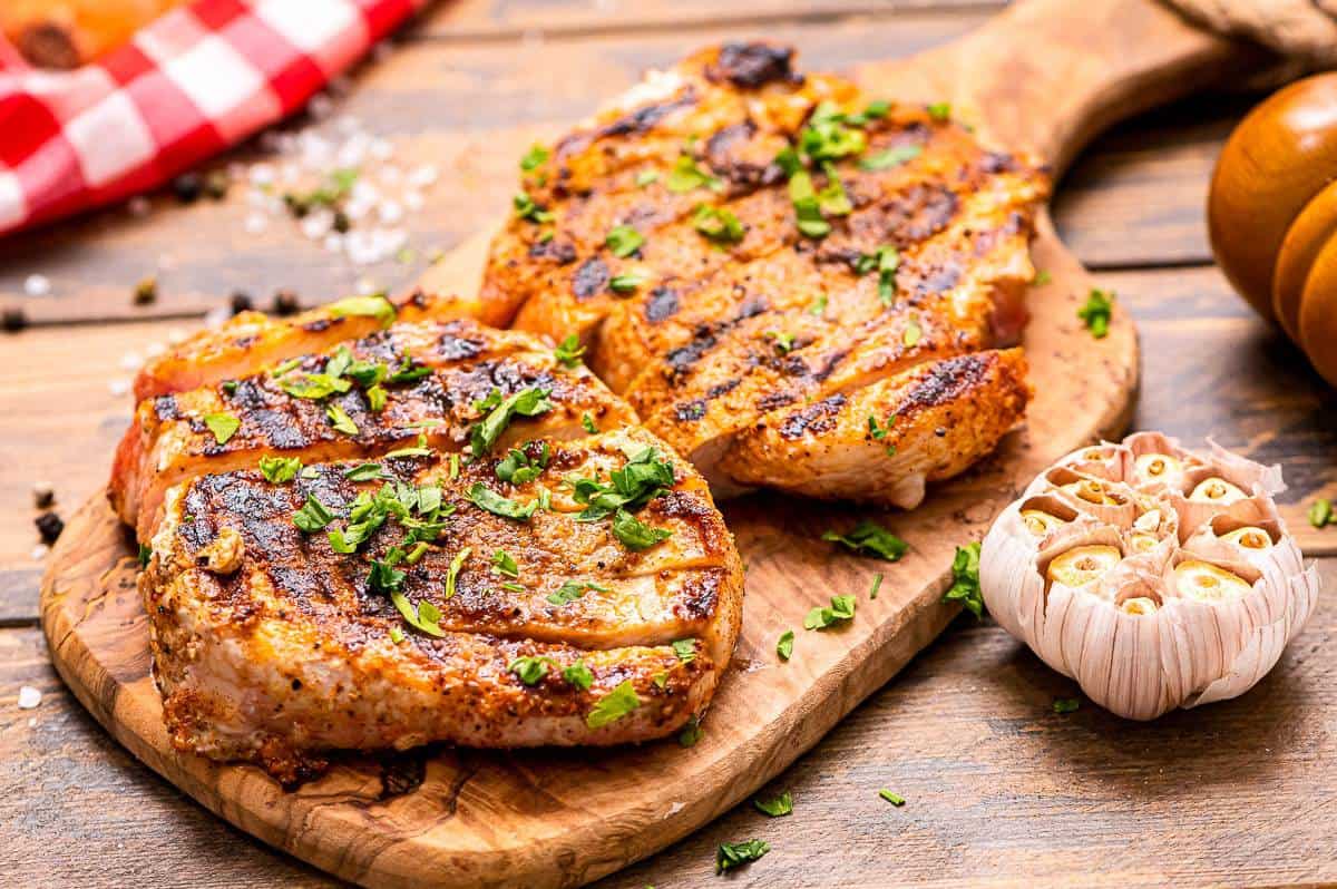 Wood cutting board with cooked pork chopes on it