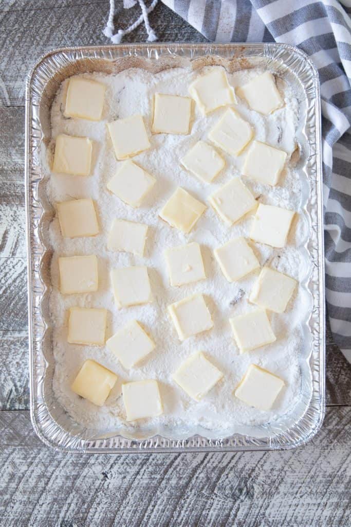 Slabs of butter evenly placed on top of cake mix in a dump cake.
