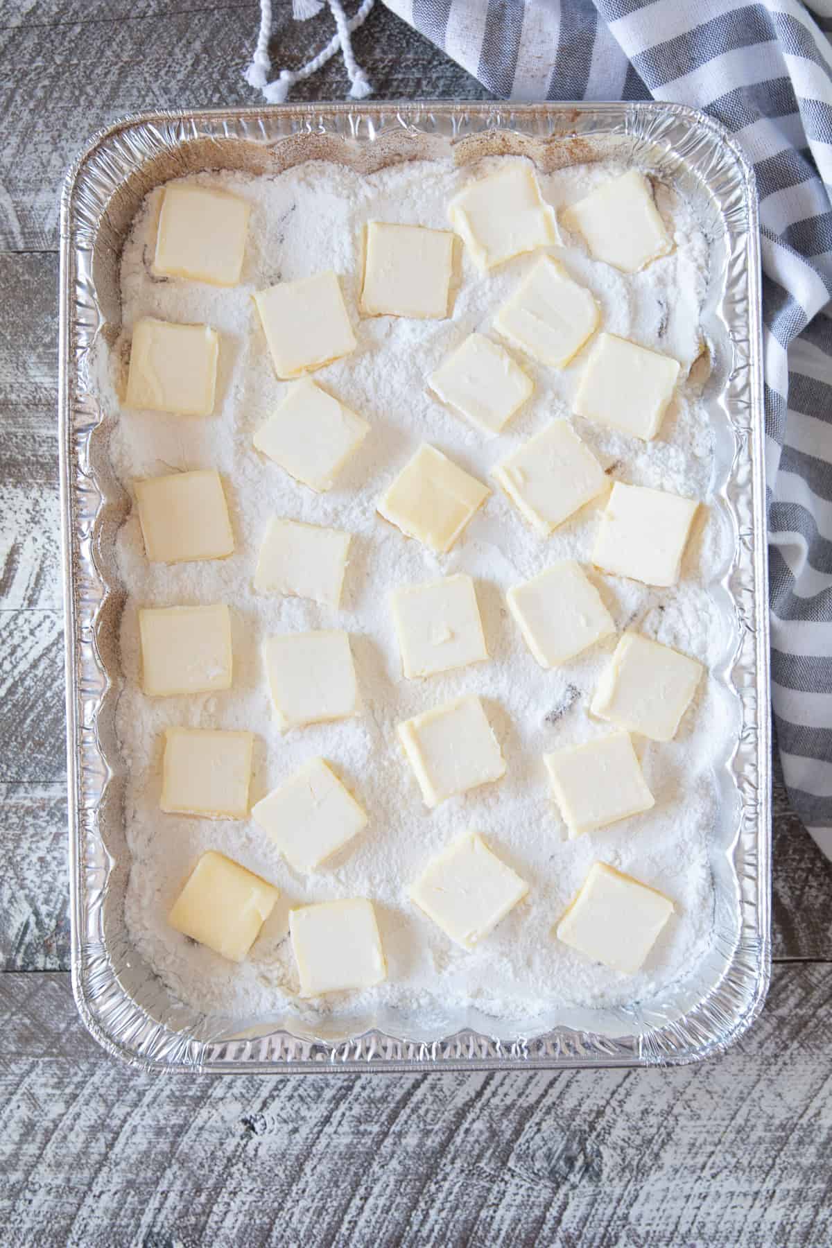 Slabs of butter evenly placed on top of cake mix in a dump cake.