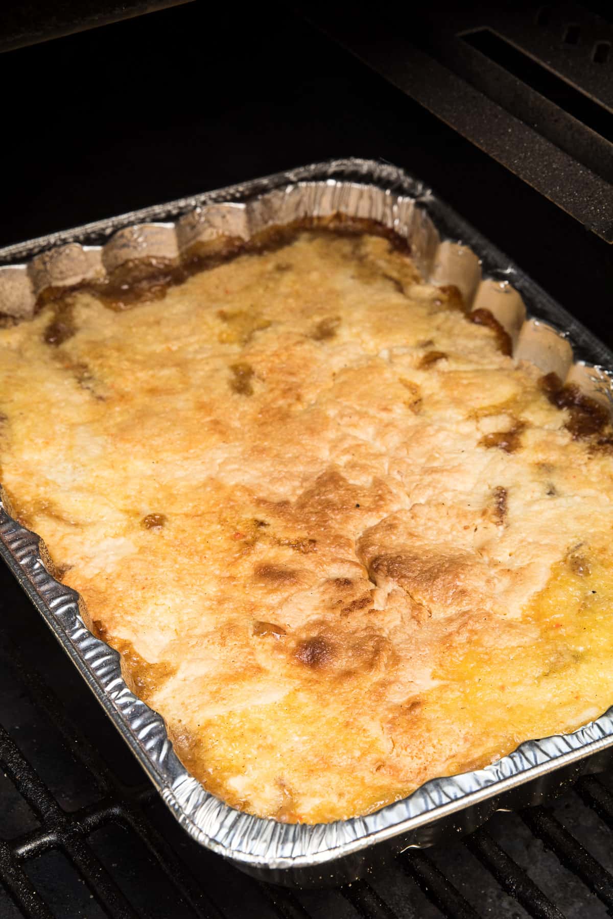 Foil pan with dump cake in it on smoker