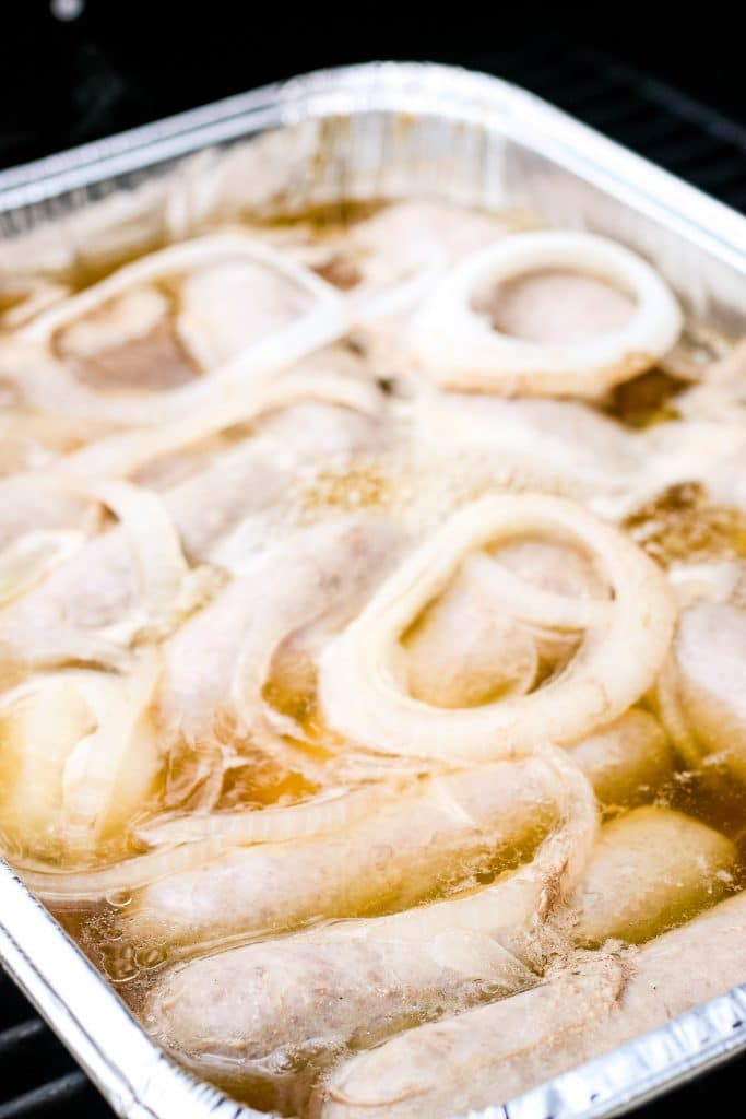 Disposable pan filled with sliced onions, brats and beer.